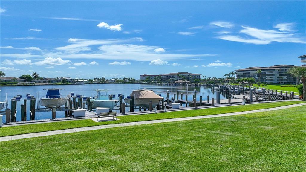 Dock featuring boat lift, a lawn, and a water view