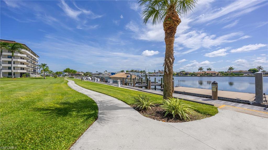 Surrounding community featuring a dock, a lawn, and a water view