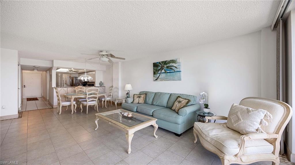 Tiled living area with ceiling fan and a textured ceiling