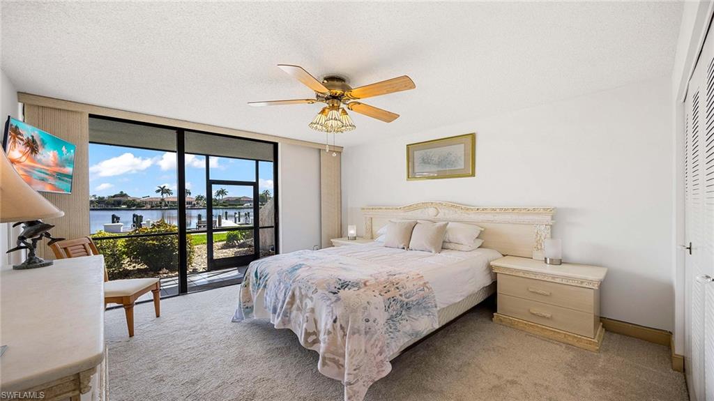 Bedroom with expansive windows, access to exterior, a textured ceiling, a water view, and carpet