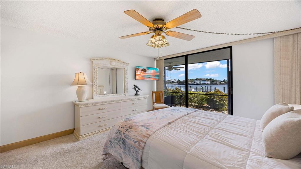 Bedroom with a textured ceiling, a ceiling fan, light colored carpet, access to exterior, and floor to ceiling windows