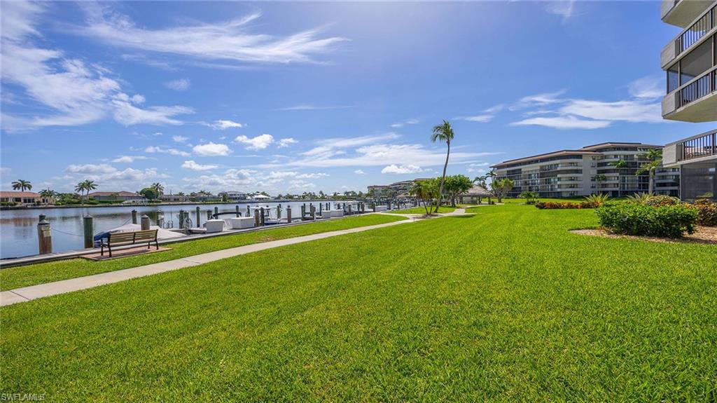 View of community with a yard, a water view, and a boat dock
