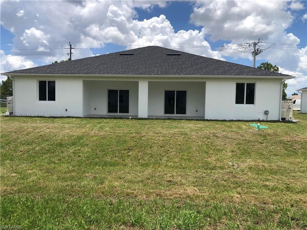 Back of house with a lawn, stucco siding, a patio area, and roof with shingles