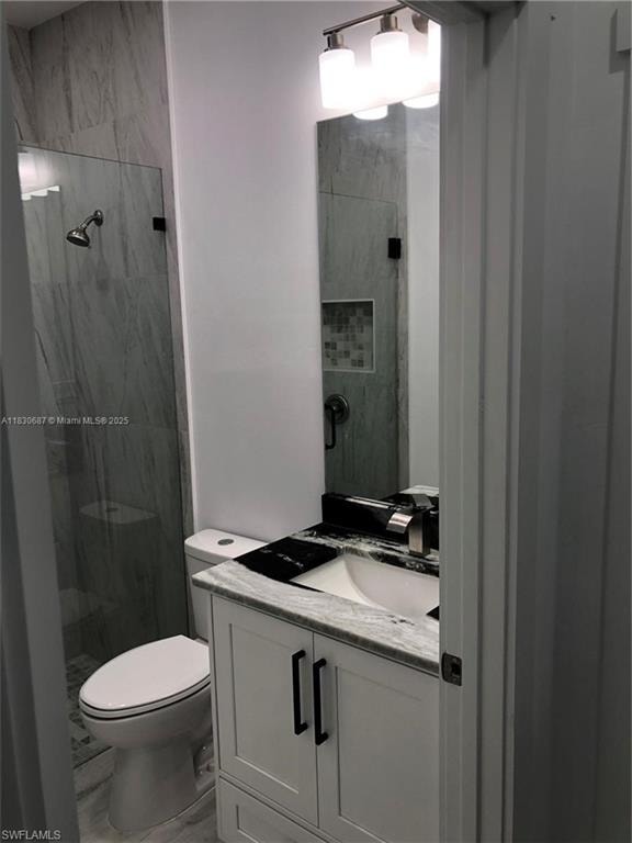 Full bathroom featuring vanity, a marble finish shower, and marble finish floors