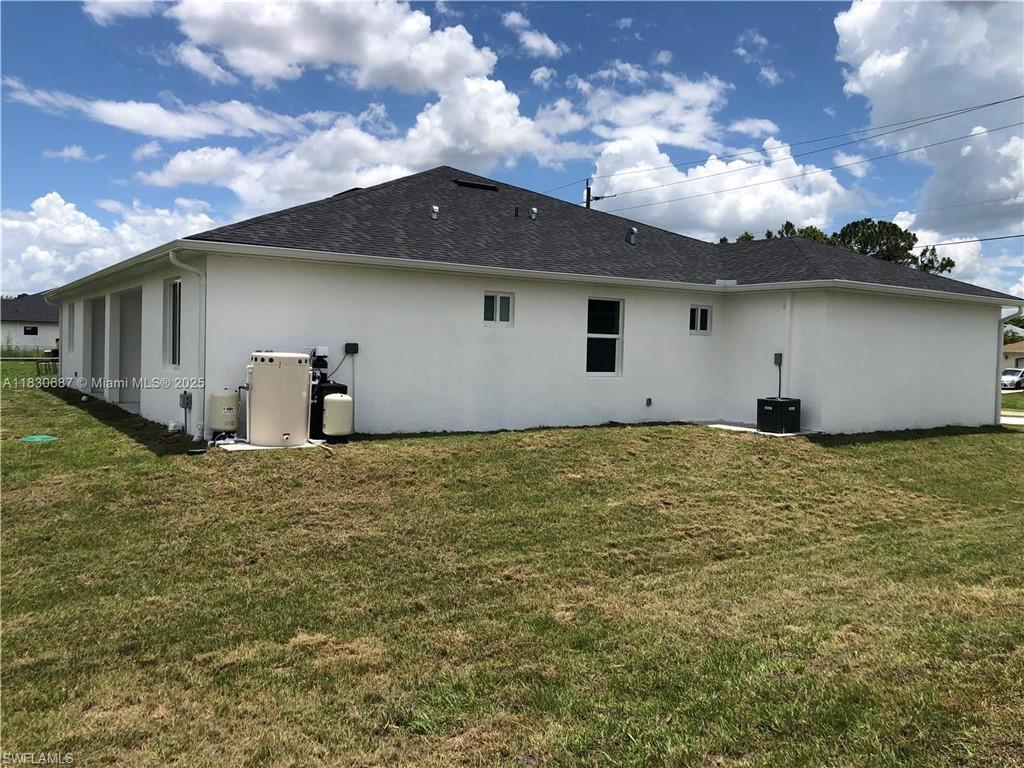 Rear view of house featuring stucco siding and a yard
