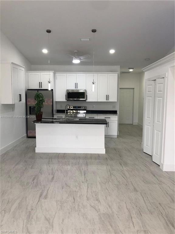 Kitchen featuring decorative light fixtures, stainless steel appliances, white cabinetry, a kitchen island with sink, and recessed lighting