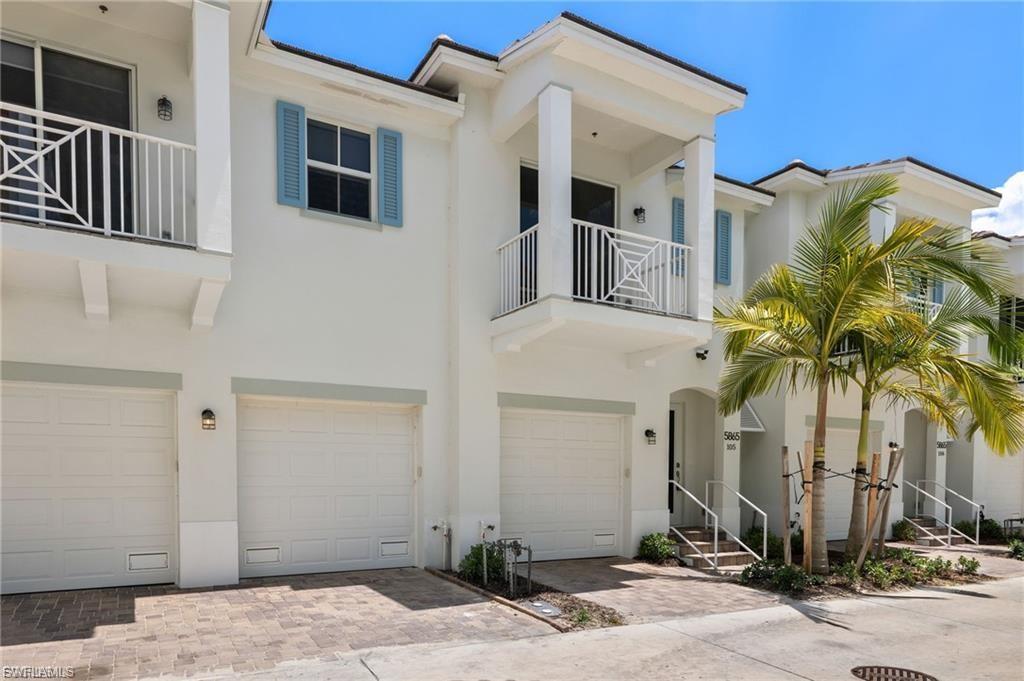 View of front of home with a balcony, stucco siding, an attached garage, and decorative driveway