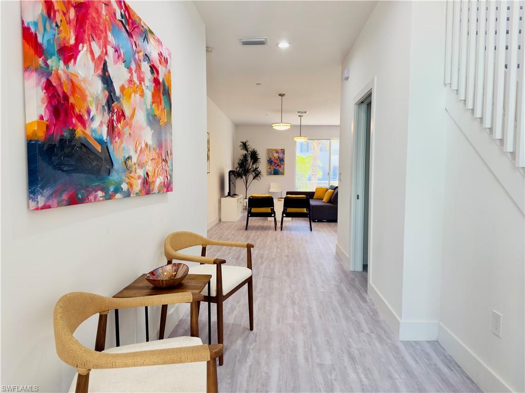 Hall featuring light wood finished floors, stairway, and recessed lighting