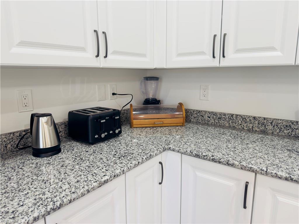 Detailed view of white cabinetry and light stone counters