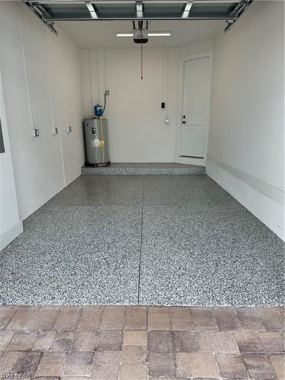 Garage featuring electric water heater and a garage door opener