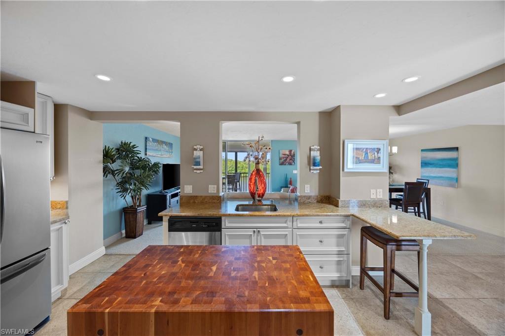 Kitchen with wood counters, a kitchen breakfast bar, kitchen peninsula, appliances with stainless steel finishes, and white cabinetry