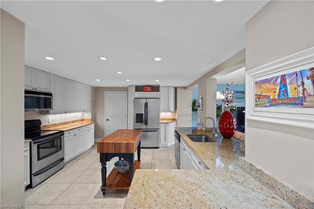 Kitchen featuring butcher block counters, white cabinetry, sink, light tile patterned flooring, and appliances with stainless steel finishes
