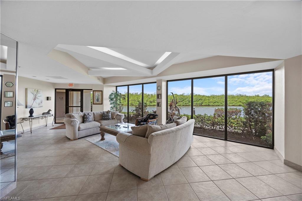 Tiled living room featuring plenty of natural light, a water view, lofted ceiling, and french doors