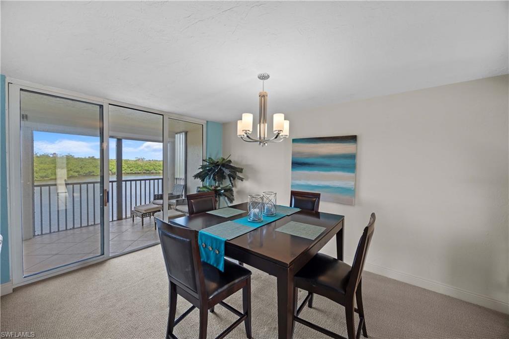 Carpeted dining space with a water view and a notable chandelier