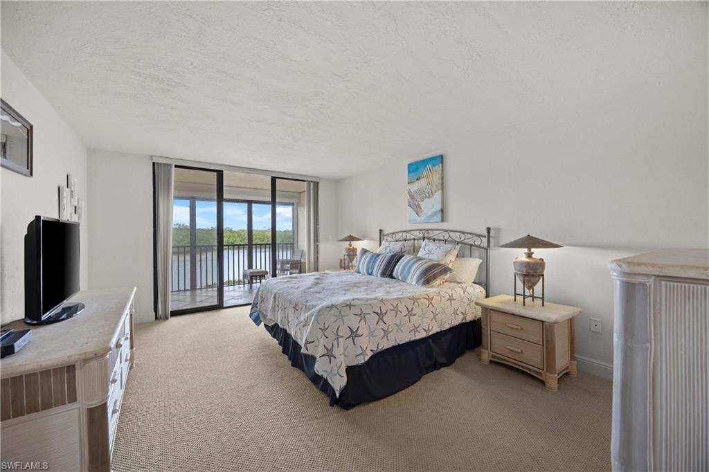 Bedroom with access to exterior, floor to ceiling windows, light colored carpet, a textured ceiling, and a water view