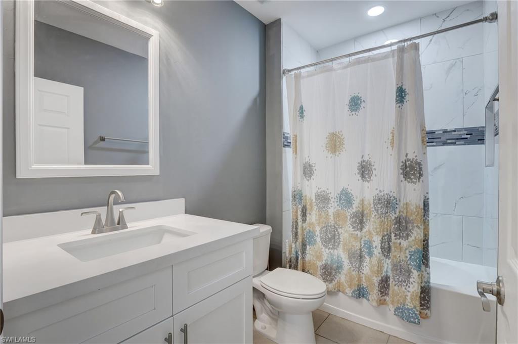 Full bath with shower / tub combo with curtain, vanity, and tile patterned flooring