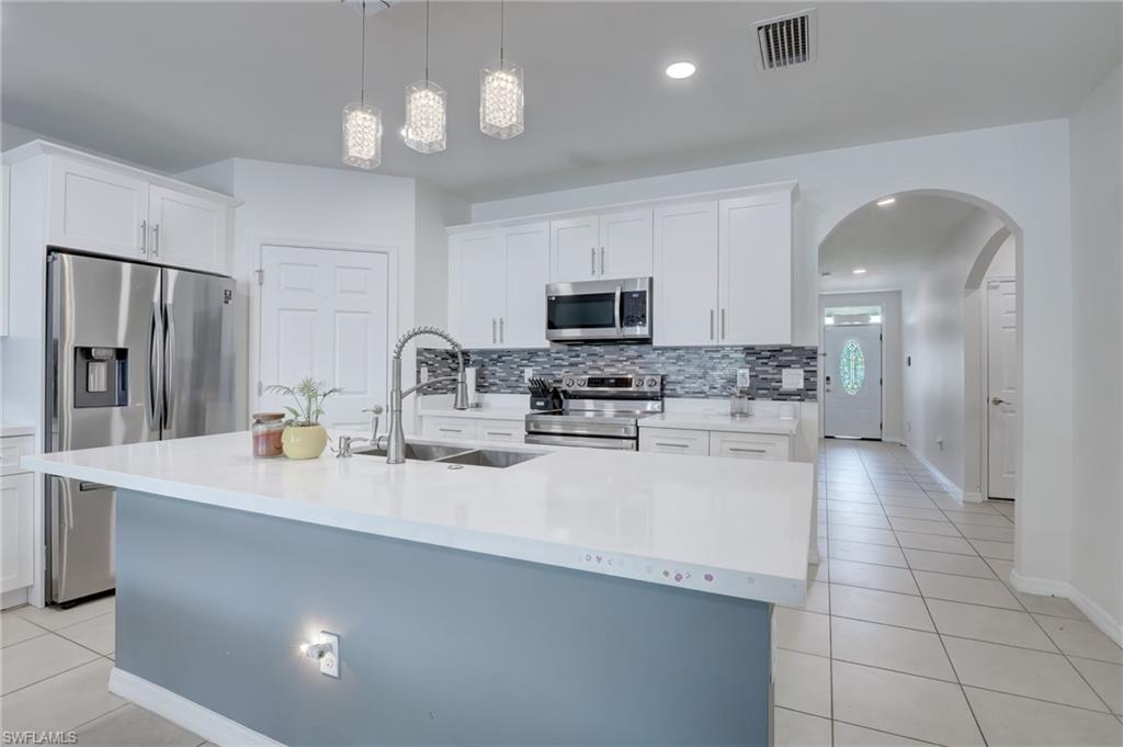 Kitchen with light tile patterned floors, white cabinets, stainless steel appliances, pendant lighting, and recessed lighting