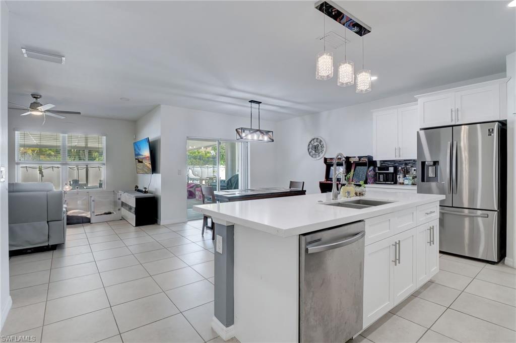 Kitchen featuring open floor plan, stainless steel appliances, white cabinets, a kitchen island with sink, and light tile patterned floors