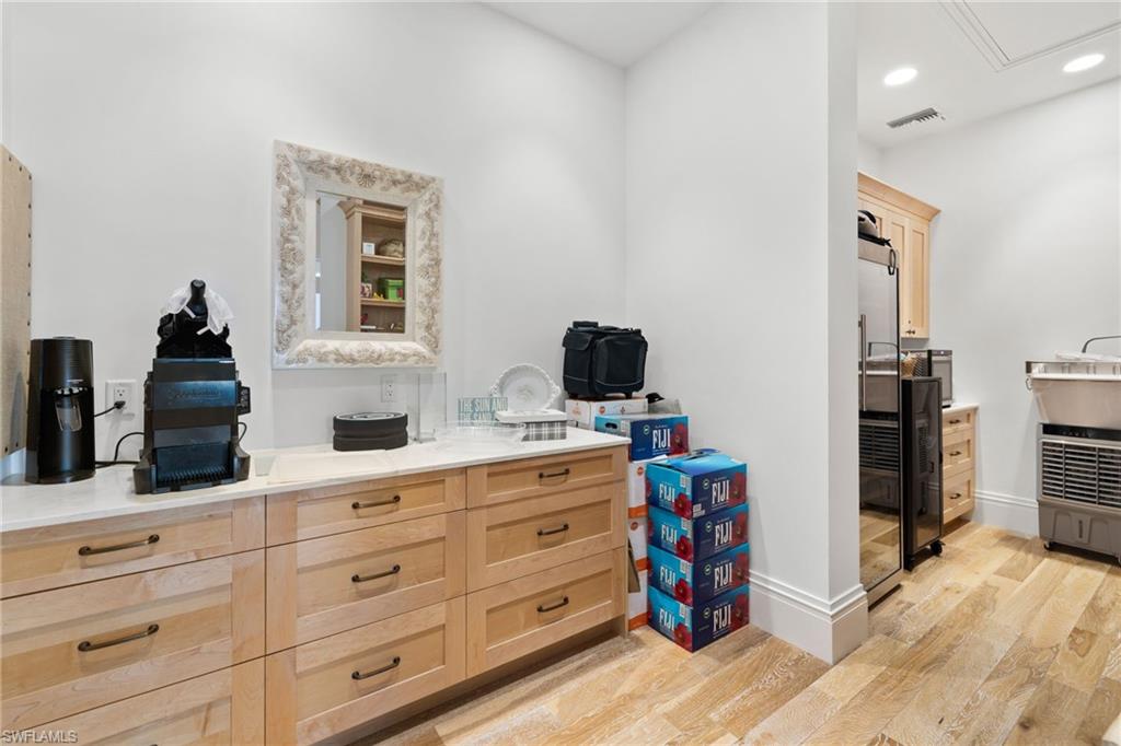 Bar with light brown cabinetry, light wood-style floors, recessed lighting, built in fridge, and light stone countertops