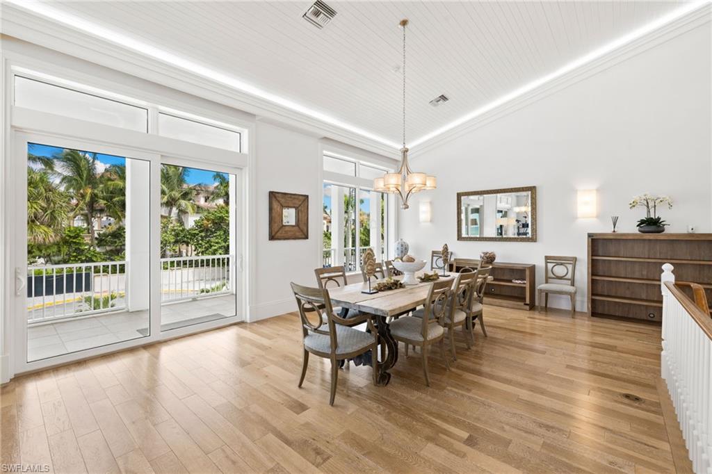 Dining room featuring light wood-type flooring, a chandelier, high vaulted ceiling, and ornamental molding