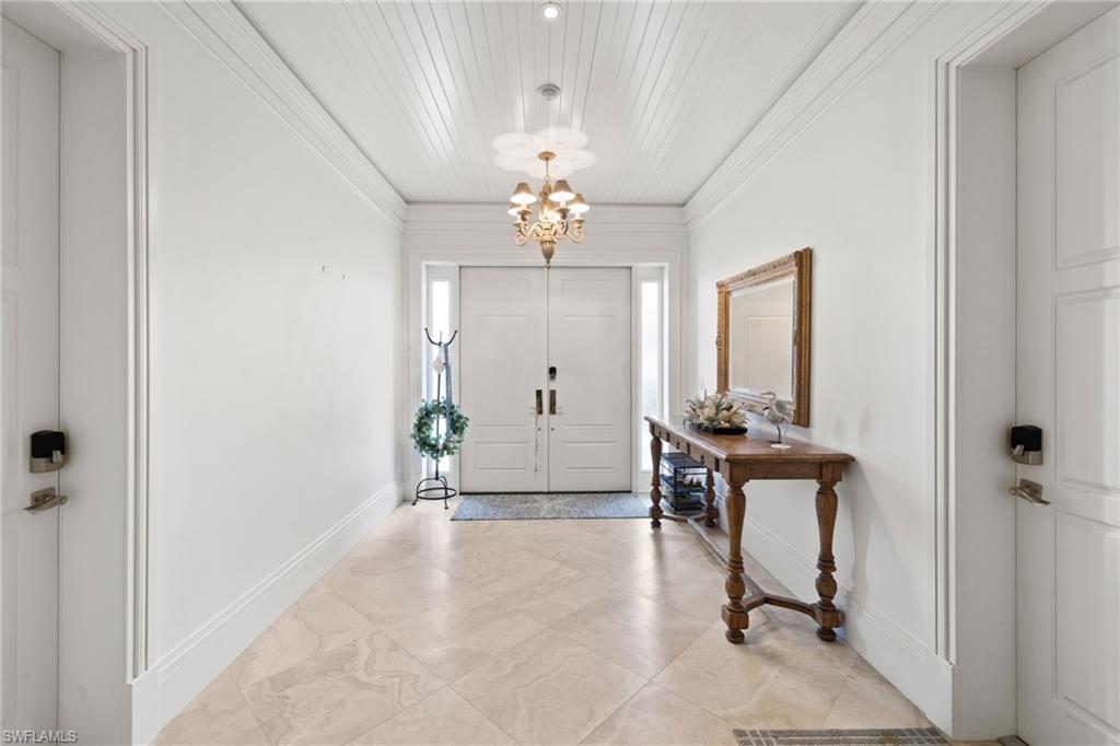 Foyer entrance featuring a chandelier, ornamental molding, and light tile patterned floors