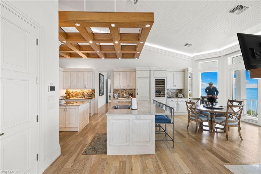 Kitchen with backsplash, light wood-style floors, coffered ceiling, light stone countertops, and recessed lighting