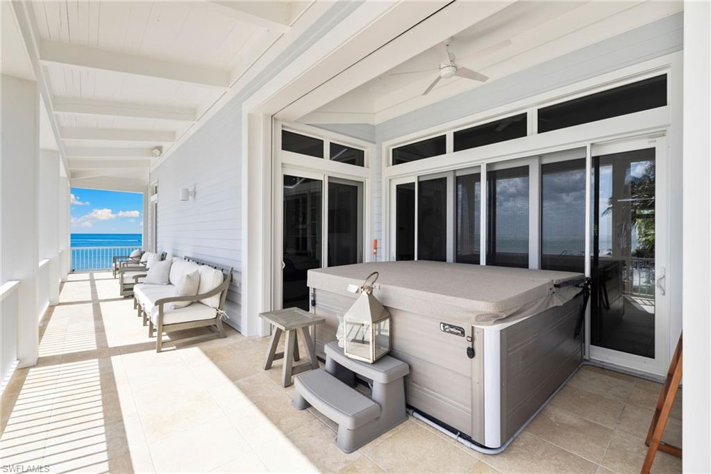 View of patio featuring a water view, a hot tub, and a ceiling fan