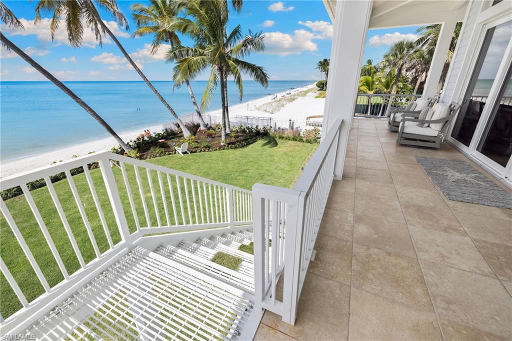 Patio / terrace with a lawn and view of water and beach