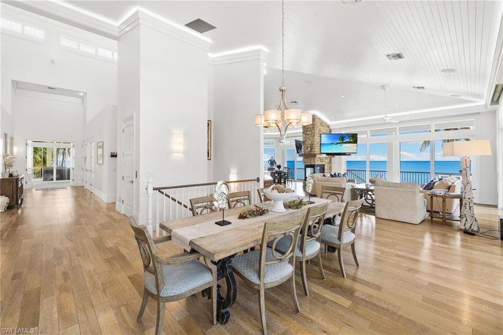Dining area with healthy amount of natural light, a chandelier, light wood-style floors, a high ceiling, and crown molding