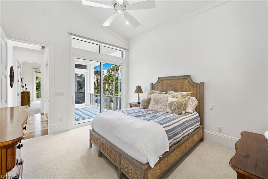 Bedroom featuring ornamental molding, lofted ceiling, access to outside, multiple windows, and a ceiling fan
