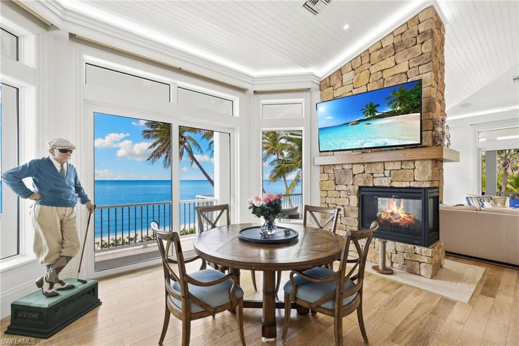 Dining area featuring a stone fireplace, hardwood / wood-style floors, vaulted ceiling, and wood ceiling
