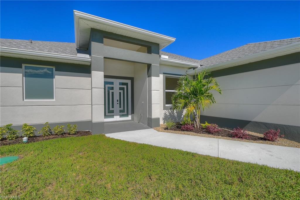 Doorway to property with a lawn, stucco siding, and a shingled roof