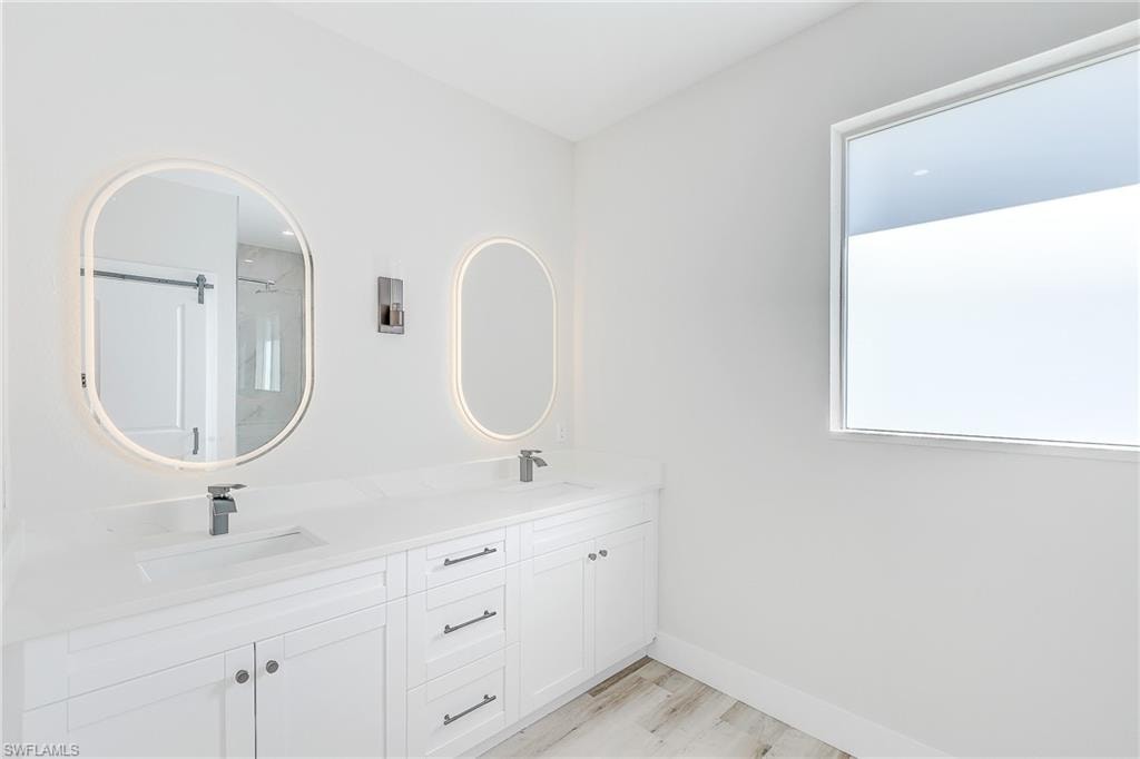 Primary bathroom featuring healthy amount of natural light, a marble finish shower, and wood finished floors