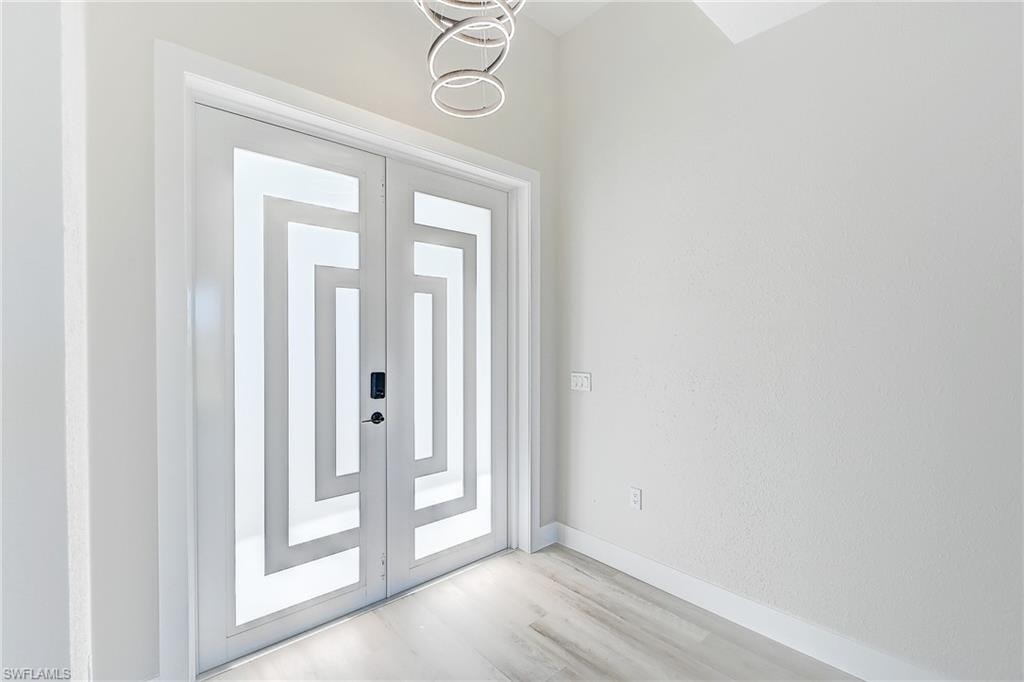 Empty room with a tray ceiling, french doors, light wood-type flooring, a ceiling fan, and recessed lighting
