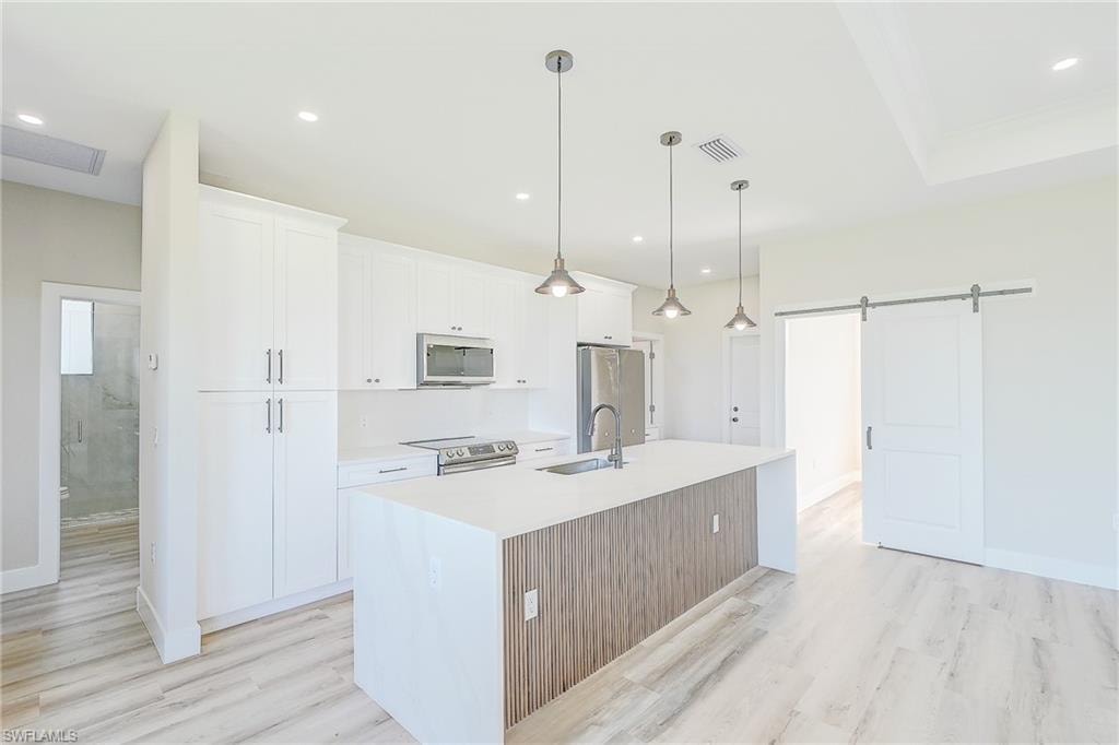 Kitchen featuring appliances with stainless steel finishes, light wood-style floors, white cabinetry, and recessed lighting
