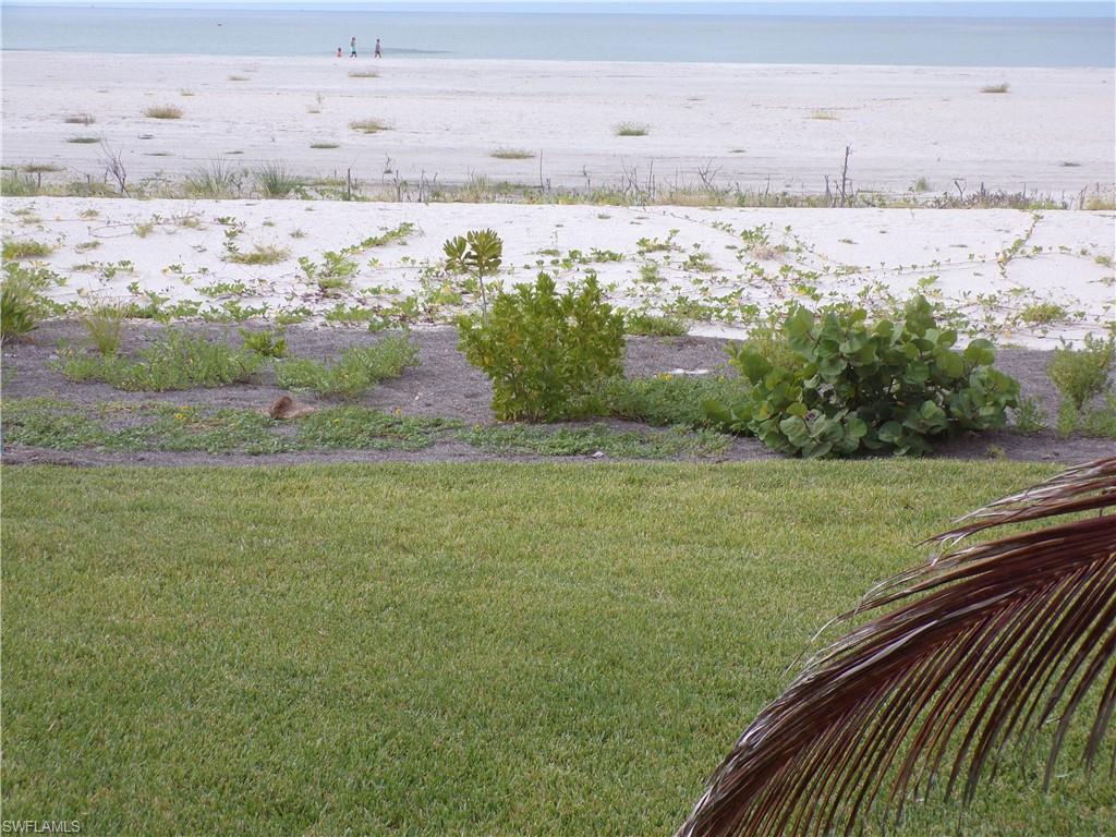 View of green lawn with view of water and beach