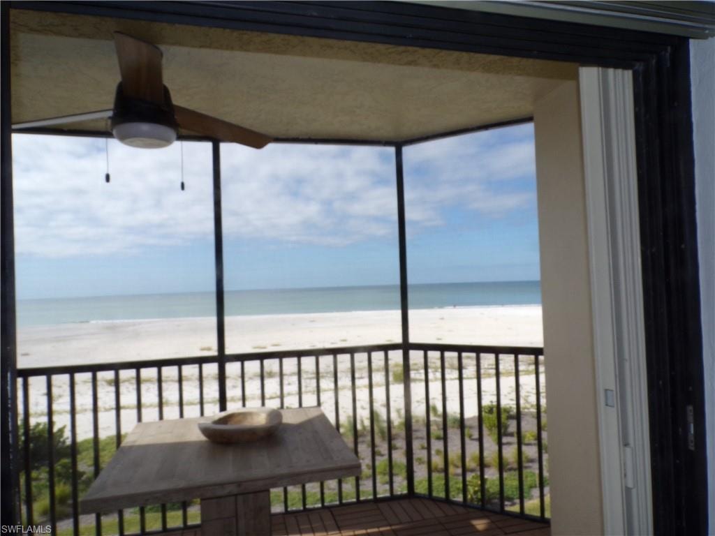 Balcony featuring a sunroom and view of water and beach
