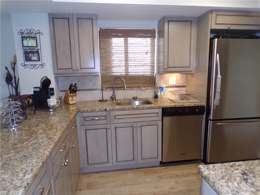 Kitchen with freestanding refrigerator, stacked washing machine and dryer, light wood finished floors, and decorative light fixtures