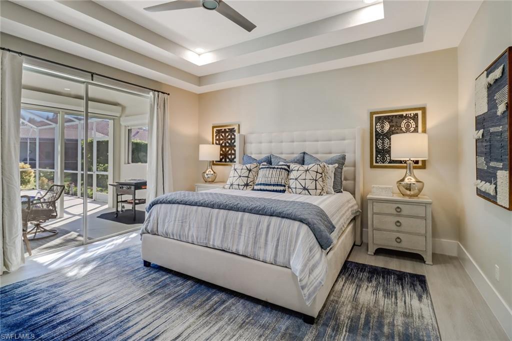 Bedroom with a tray ceiling, access to outside, ceiling fan, and wood finished floors
