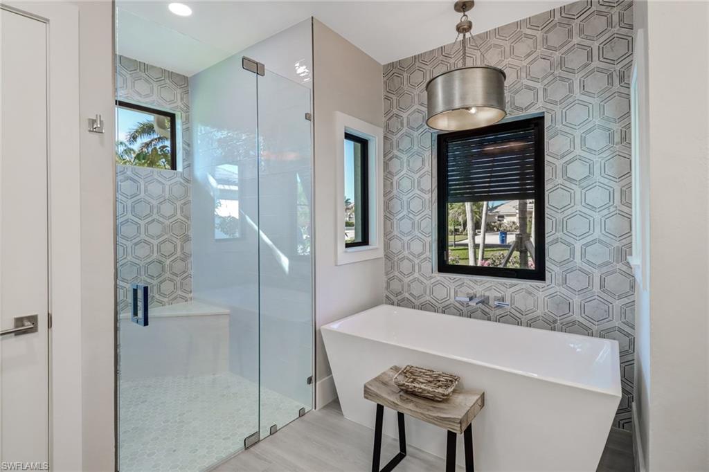Bathroom featuring a freestanding bath, a shower stall, recessed lighting, and wood finished floors