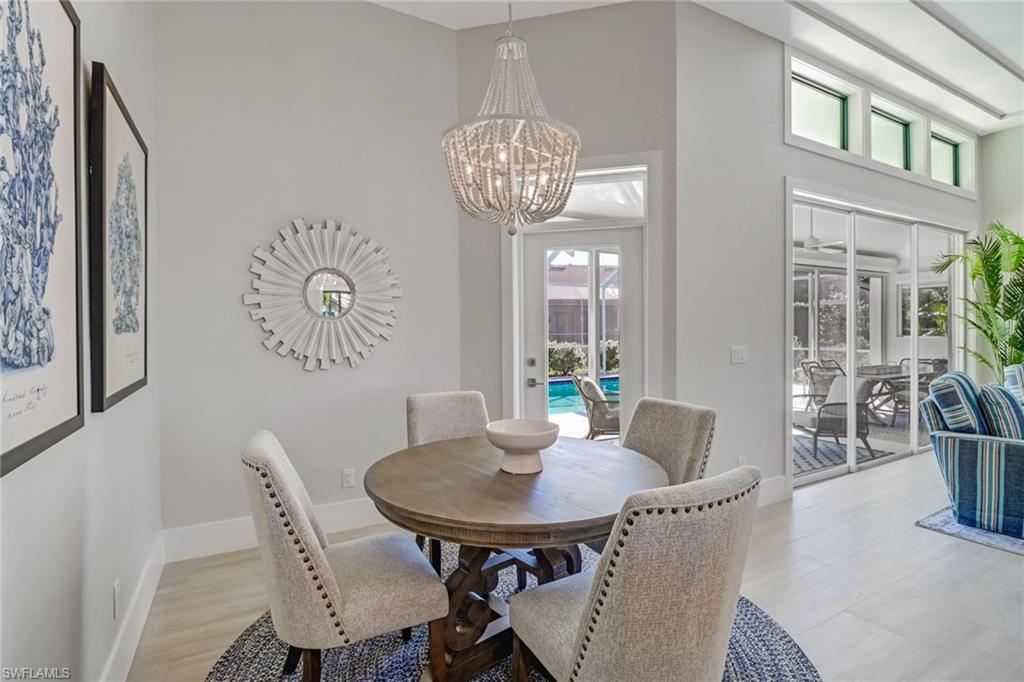 Dining room with a high ceiling, plenty of natural light, a chandelier, and light wood-style flooring