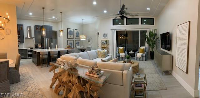 Living room with a ceiling fan, recessed lighting, light wood-style floors, and a chandelier