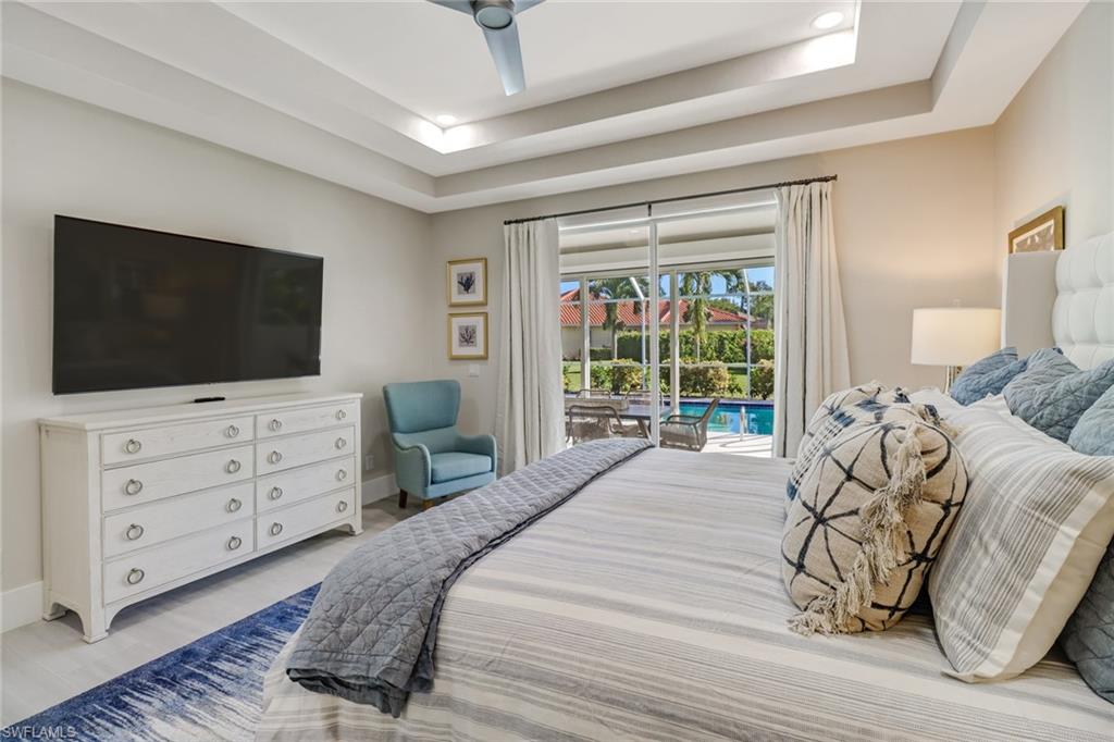 Bedroom featuring a raised ceiling, access to outside, ceiling fan, light wood-style flooring, and a sunroom