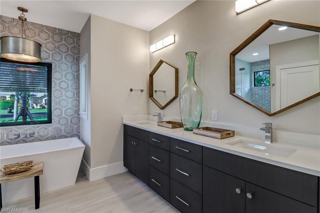 Full bathroom with double vanity, a freestanding bath, and light wood-type flooring