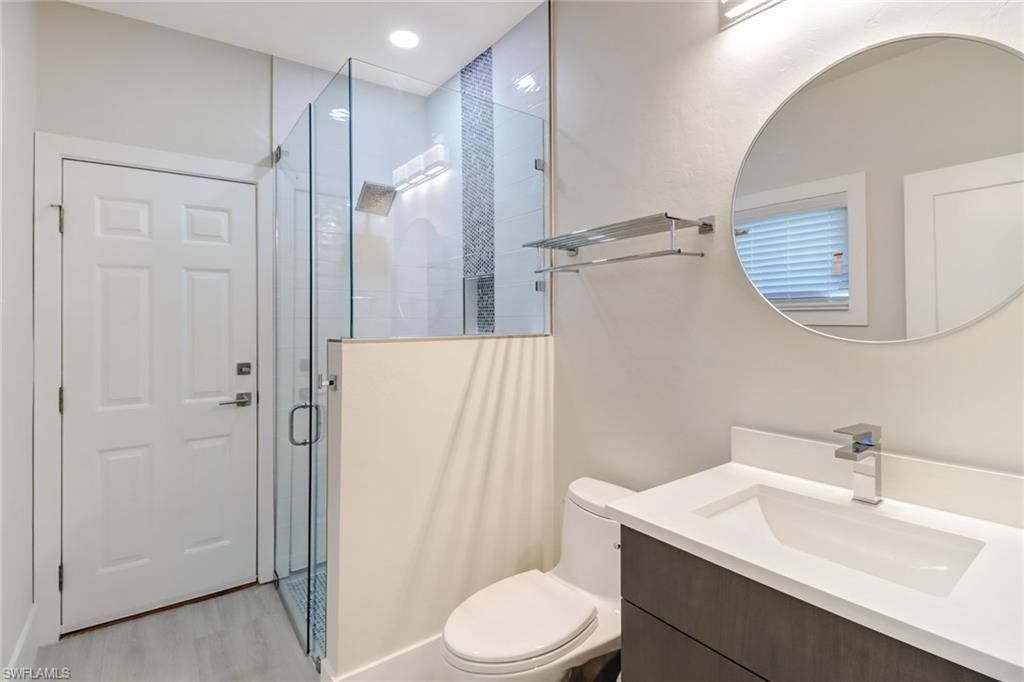 Bathroom with vanity, a shower stall, and light wood-style flooring