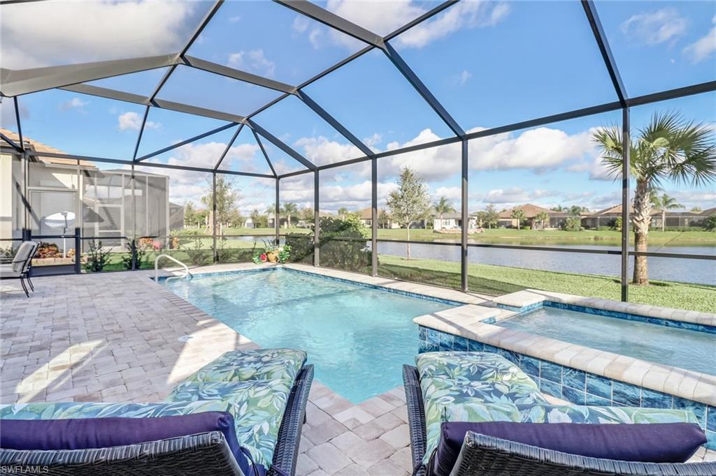 View of pool with a sunroom, a water view, glass enclosure, and a pool with connected hot tub