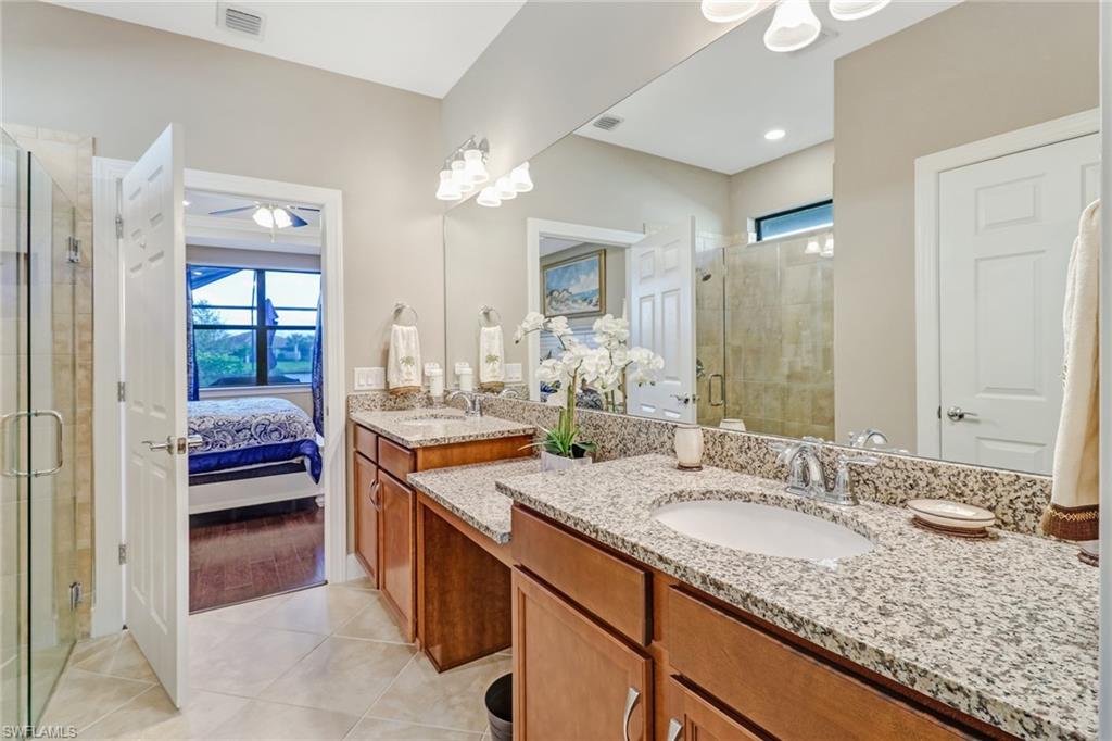Bathroom with plenty of natural light, ensuite bath, double vanity, and a stall shower
