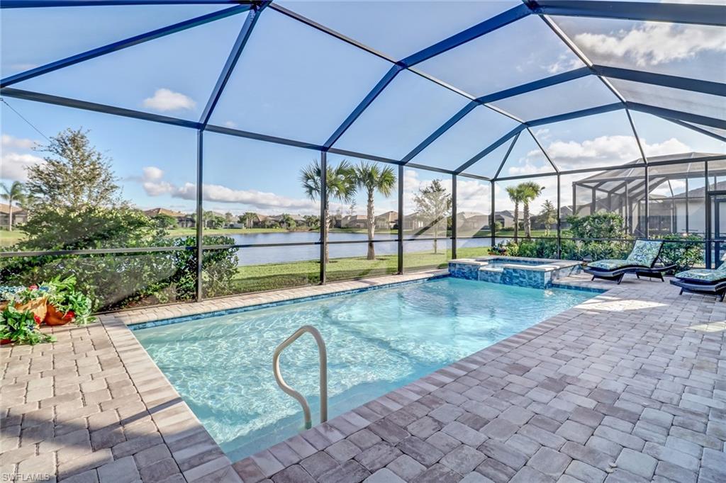 View of swimming pool with a sunroom, a residential view, a water view, a pool with connected hot tub, and glass enclosure