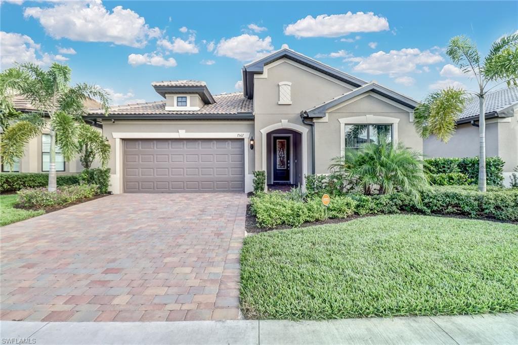 Mediterranean / spanish house featuring stucco siding, decorative driveway, a tiled roof, an attached garage, and a front yard