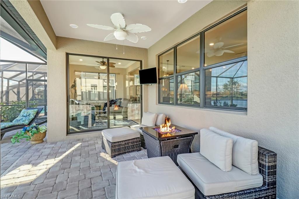 View of patio featuring a sunroom, ceiling fan, an outdoor living space with a fire pit, and a lanai
